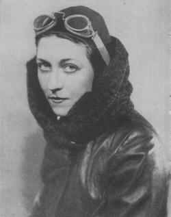 Black and white portrait photograph taken around 1930 of Amy Johnson, wearing aviator attire; googles, leather cap, leather and wool flying jacket