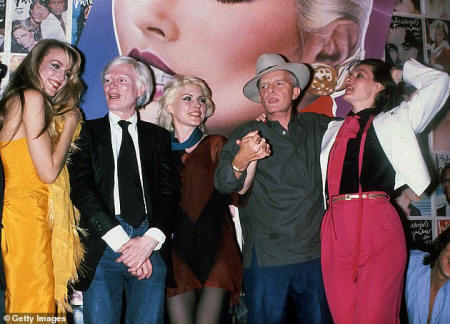 Warhol was 'utterly immersed' in the gay community of Manhattan and one Halloween he turned up to a party wearing a garland of flowers, as 'daisy chain' was gay slang for a round robin orgy. Pictured: Warhol with Jerry Hall, Debbie Harry, Truman Capote and Paloma Picasso at Studio 54  circa 1970s